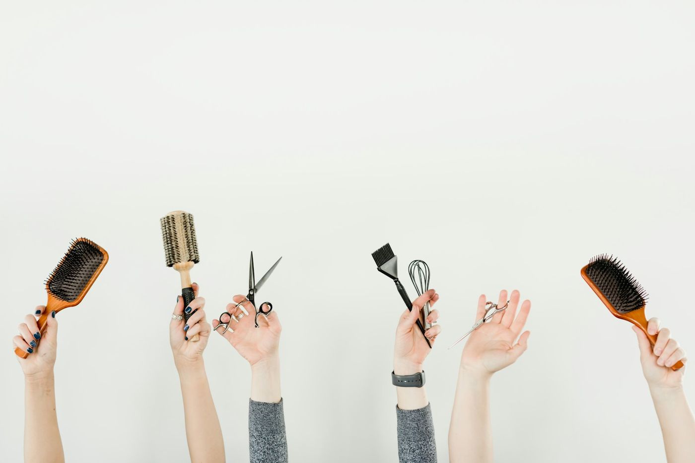 Hands holding up brushes, scissors and combs