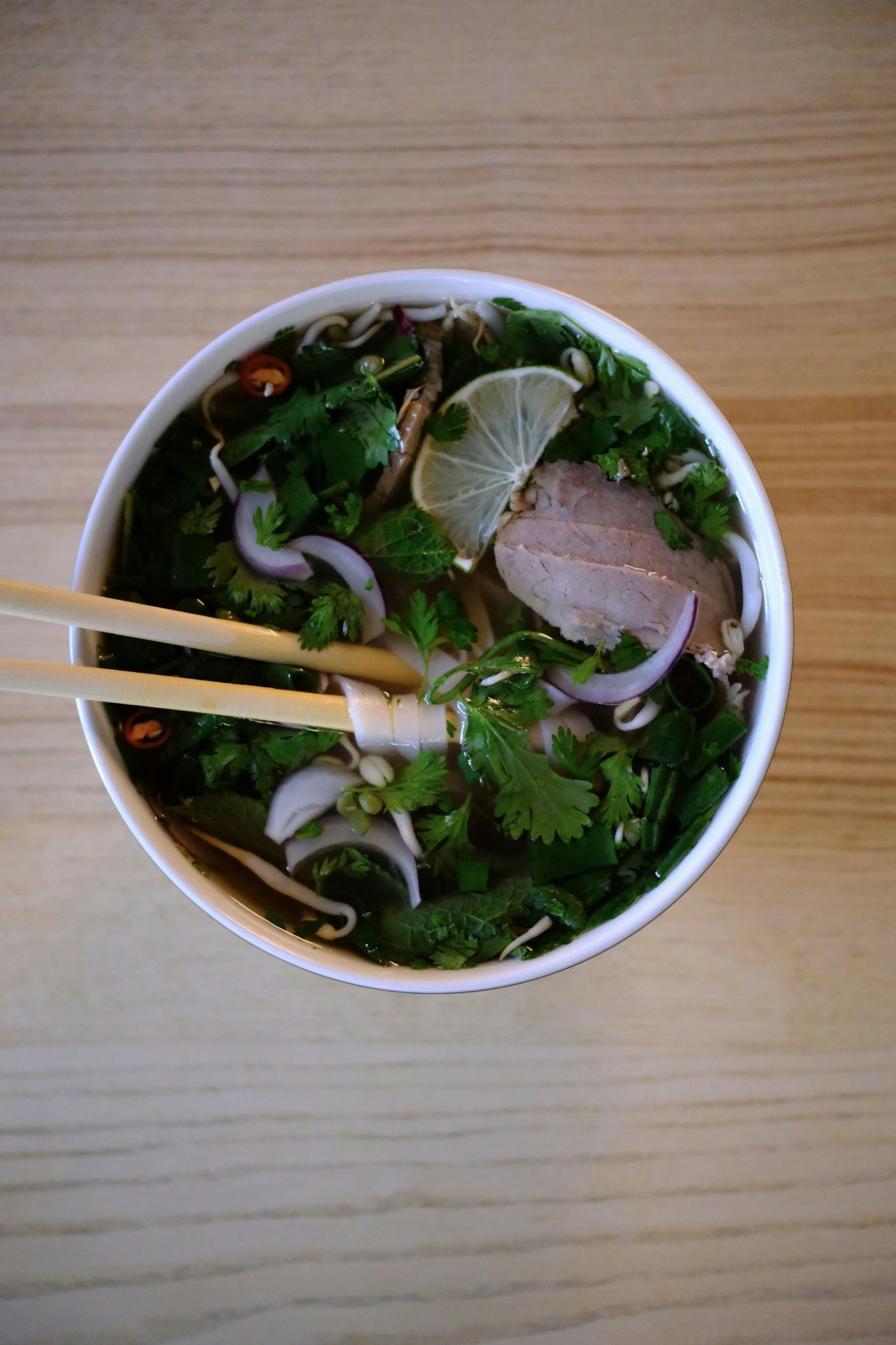 Phở from above with herbs, lime and chopsticks